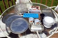 Overview of lot showing pizza pans, loaf pan, ice tray, mugs, plastic dome, stack of bowls