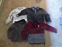 All three garments laid out: beige Izzi shell with brown fleece, black Totes jacket, maroon/grey Disney fleece