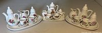 All three complete miniature tea sets side-by-side showing component pieces and patterns