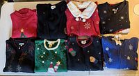 Eight folded Christmas sweaters displayed on table
