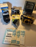 Group shot showing all photographic items including cameras, flash, viewer, film and mounting corners