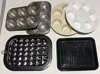 All six baking pans laid out: two metal muffin tins, two round microwave muffin pans, two broiler pans