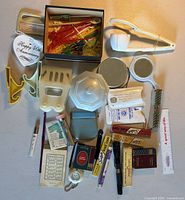 All items laid out including ceramic dish, cocktail picks, kitchen tools, sewing notions, vanity items, lighter, tape measure, pen and other small gadgets