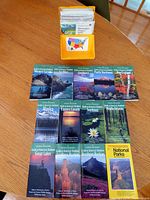 Group shot of eleven National Geographic guide books laid out on table in three rows with yellow plastic map case behind