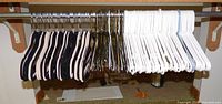 Row of black velvet, metal wire and white plastic hangers on closet rod