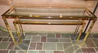 Full view of brass-tone metal sofa table showing glass top, glass shelf and overall condition