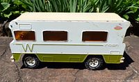 Left side profile showing olive lower body, white upper, green W graphic, amber windows, rubber tire, overall wear
