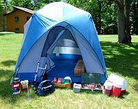 Full lot showing pitched tent, stoves, lantern, coolers, bike rack, poles, backpack