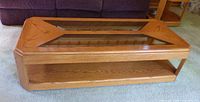 Full front view of wooden coffee table with glass inserts and shelf