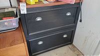 Front view showing two drawers with silver cup pulls, black finish