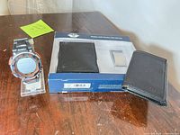 Armitron watch on stand next to Dockers wallet and boxed wallet with money clip