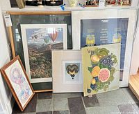 Group view of all five framed artworks leaning against wall