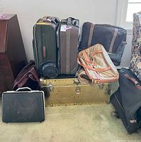 Group shot showing steamer trunk, two suitcases, garment bags and briefcase
