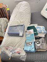 All items grouped on bed including body pillow, sheet set, towels, pillow protector, microfiber cloths