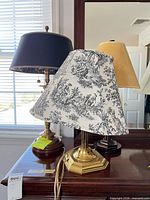 Full view of brass-tone lamp with toile shade on dresser