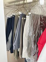 Multiple pairs of trousers on hangers in closet