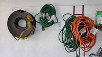 Full view of CordWheel reel with yellow cord and two green cords and orange cord hanging on wall