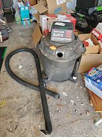 Craftsman 16-gallon wet/dry vacuum with hose, wand and nozzle visible on garage floor
