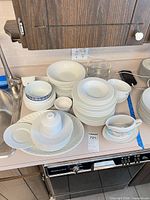 Full set stacked on counter showing variety of plates, bowls, gravy boat, sugar jar