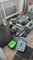 Mower folded with battery installed, charger and bag visible