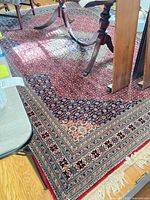 Top view of rug showing red field, navy and cream borders under dining table legs