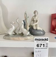 Overview of both Lladro figurines on shelf, mermaid and ducks visible