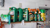Shelf with eight garden chemical containers including Ortho weed killers and Miracle-Gro fertilizers