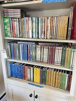 Three shelves filled with sealed DVDs, color-coded spines