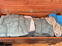 Folded blue jacquard panels, white liners and lace doily inside cedar chest