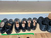 Row of five pairs of black shoes on shelf
