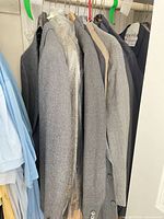 Multiple gray sport coats on hangers in closet