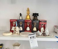 Shelf view showing boxed bells, loose metal bells, porcelain plaque and mini tea set