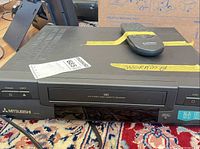 Front and top view of Mitsubishi HS-U410 VCR with remote on top