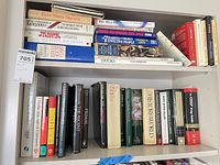 Two shelves of assorted books showing spines and stacked volumes