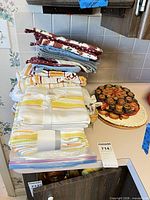 Stack of tea towels, mitts, pot holders beside straw trivets on countertop