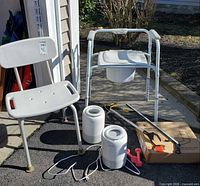 Full lot showing commode chair, shower chair, two humidifiers, grabber tool, bed rail box and dumbbells