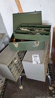 Overall lot showing metal toolbox on top of two drawer cabinets