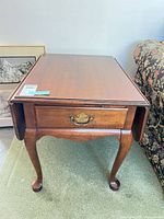 Front view showing drawer, cabriole legs, drop leaves folded