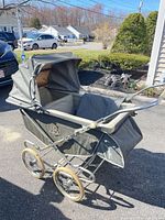 Full view of gray Storkline pram showing frame, wheels and canopy