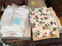Stack of white embroidered linens and fruit print placemats