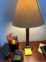 Lamp, pen holder, adapter plug visible on wooden surface