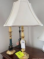 Two of the lamps on table showing brass and faux-marble columns and shades