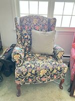Front view of floral wingback chair with pillow