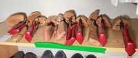 Row of cedar shoe trees with red handles on shelf