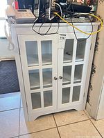 Front view of white cabinet with glass pane doors and metal knobs