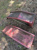 Two red metal car ramps on ground