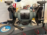 Front view of Delta bench grinder with wheels, extra wheel and diamond dresser visible