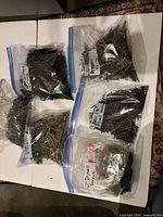 Overview of five ziplock bags filled with drywall screws and nails