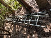 Full view of collapsed aluminum extension ladder lying on ground