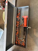 Open grey toolbox showing numerous orange-collated drive pins, Ramset driver with orange handle